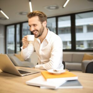 Smiling teacher enjoying coffee while working on a laptop, preparing lessons with AI tools