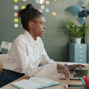 Woman working on a laptop at a desk, representing the Advanced AI in TESOL course